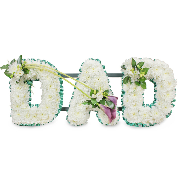 Captured against a bright white background, this image features a personalised funeral tribute spelling out DAD in large, three-dimensional floral letters, created with the kind of care you might expect from a dedicated Stanmore florist. Each letter is meticulously covered with small white chrysanthemums, packed closely together so their rounded, daisy-like heads form a smooth, continuous surface. The pristine petals overlap slightly, catching the light in gentle highlights while soft shadows settle in the spaces between, giving the arrangement a plush, cushion-like appearance that feels comforting and serene. Around the perimeters of the letters, an emerald green satin ribbon is carefully ruffled and pinned, hugging every curve and edge to define the shapes with crisp precision. This border adds a touch of richness and mirrors the verdant feel of Stanmore's tree-lined avenues and green open spaces. Subtle glimpses of dark structural bars behind the letters reveal the sturdy frame that allows the piece to stand upright during a service or graveside committal.   

Thoughtful accent flowers bring individuality and emotional nuance to the design. On the first D, a dainty arrangement of white freesia blooms and polished green leaves sits at the upper left curve. Some flowers are fully open, while others remain in bud, suggesting ongoing love and memories that continue to unfold. From this focal point, two long, slender green stems sweep diagonally across the composition toward the central A, visually binding the letters together like a ribbon of shared family history. At their meeting point lies an elegant, slightly off-centre spray composed of two deep purple calla lilies surrounded by more white freesia and lush foliage. The calla lilies' velvety, trumpet-shaped blooms add a note of depth and gravity, their darker hue standing out against the white without overpowering it. On the final D, a smaller echoing cluster of freesia and foliage rests at the top right, completing the visual rhythm. Overall, the tribute conveys quiet strength, enduring affection, and gratitude for a father's presence, a fitting floral memorial for families in Stanmore seeking a meaningful way to say goodbye.