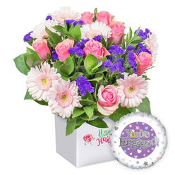 From Flowers Stanmore, this vibrant engagement bouquet arrives in a pristine square white presentation box, its front adorned with a small red rose emblem and fresh green script. The bouquet assembles a generous mix of soft pink roses in various stages of bloom-from neat buds to fully opened petals-surrounded by pale pink gerberas with crisp white edges and sunny pale centers. Sprigs of deep purple statice provide rich contrast, while lush green foliage layers the composition like a garden moment captured indoors. The arrangement sits as if painted against a backdrop of Stanmore's leafy streets, ready to bring warmth to a doorstep on The Broadway or near Stanmore Village. To complete the gift, a round foil engagement balloon rests to the lower right, its central panel a rich violet field with the message 'You're Engaged!' in silver lettering, the 'O' stylized as a golden ring. A white rim frames the portrait, and a scattering of tiny pink, blue, and white hearts plus silver stars adds whimsy. This bouquet is designed for immediate delight, available for same-day delivery across Stanmore, Edgware, and surrounding postcodes, making it a thoughtful way to toast a couple starting their new chapter.