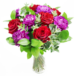 In this sophisticated bouquet, rich red roses and generous purple peonies are arranged with the polish of a seasoned Stanmore florist, creating a centrepiece that feels both opulent and beautifully composed. The roses are a deep, velvety crimson, each bloom fully open yet still structured, their petals forming precise, spiralling layers that exude warmth, love, and a touch of drama. Interspersed between them, the purple peonies form large, rounded blossoms, with ruffled petals packed tightly together to create a soft, cloud-like effect. The interplay between the intense red and cool purple tones is striking but never harsh, softened by an abundance of fresh greenery at the base. Smooth, dark green leaves provide a rich backdrop, while delicate, slightly arching stems of eucalyptus add a note of silvery freshness, their rounded leaves introducing a gentle sense of movement. All of this is gathered into a simple, clear glass vase, its clean lines drawing the eye upward to the flowers while allowing the stems and their natural crossing patterns to show beneath the surface of the water. The lighting in the image feels like soft afternoon sun, perhaps filtering into a home near Stanmore station or along Old Church Lane, making the petals glow and casting subtle shadows that enhance the textures. In your mind, the bouquet carries a gentle scent: the classic sweetness of roses, tempered by the crisp, green aroma of eucalyptus and leafy stems, like a breath of fresh air after rain. This design is ideal for marking personal milestones, complimenting an intimate dinner, or sending same-day congratulations across Stanmore, communicating care, pride, and affection through its rich colours and considered, professional arrangement.