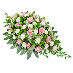 Against a clean white backdrop, this large sympathy spray stretches diagonally like a soft, floral tear, wider and more rounded at the top left and gradually narrowing to a slender point at the bottom right. A generous cluster of pink roses dominates the design, their petals unfurling in gentle spirals that give each flower a sense of quiet elegance. The pinks range from very pale, almost shell-like tones to slightly richer rose shades, bringing subtle depth to the arrangement. Between and around the roses, ruffled white carnations and spray carnations nestle closely, their frilled petals creating a light, cloud-soft texture that brightens the whole piece. The flowers emerge from a lush foundation of foliage: deep green, glossy leaves provide structure and weight, while circular eucalyptus leaves in a soft, silvery green thread through the design, hinting at a cool, fresh fragrance. From the tapered end of the spray, slender, dark green trailing foliage arcs outward, giving the composition a gentle sense of flow, as if the flowers are quietly cascading. The overall impression is one of serenity and refined beauty, the kind of arrangement that might accompany a farewell service in Stanmore, perhaps on a casket or as a focal tribute in a chapel. Designed with sensitivity and precision, it reflects the care of an experienced local florist who understands how important these details become on a day of remembrance. Every element, from the softness of the petals to the polished foliage, works together to convey sympathy, respect, and enduring love when words alone feel insufficient.