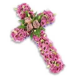 A graceful floral cross, rich in texture and softly coloured blooms, is shown against a clean white backdrop that lets the flowers take centre stage. The cross itself is three-dimensional and thoroughly covered in carefully placed blossoms, so the underlying structure is entirely hidden beneath a cushion of petals in soft pink, mauve, and lilac tones. At the heart of the design, where the two arms meet, three larger roses in a muted dusty rose shade provide a serene focal cluster. Their petals, slightly curled at the edges and full at the centre, create a sense of gentle openness. Surrounding these roses is a halo of green, formed from light, feathery fern tips and more compact leaves that bring lively contrast and texture. The rest of the cross is adorned with trumpet-shaped lisianthus, their petals slightly ruffled and their colours ranging from tender blush to deeper pinks with darker throats. These blooms flow along the arms and base like a soft floral tapestry. In between them, tiny pink and purple flowers, pale green buds, and assorted small white blossoms offer fine points of interest that catch the eye. Just at the borders, faint glimpses of slender, dark purple ribbon or fabric appear, subtly framing the overall silhouette. The composition is both tender and dignified, a fitting expression of sympathy and faith. It resembles the kind of thoughtful funeral cross a Stanmore family might request from Flowers Stanmore for a service at a local church, providing comfort and a beautiful focal point as loved ones gather to remember and say farewell.