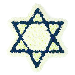 In this image, a large Star of David funeral arrangement stands out with striking clarity, its six points perfectly balanced against a bright, seamless white background. The design is composed entirely of densely packed flowers in two main shades: luminous white and a dark, almost midnight blue. A broad outer border of white chrysanthemums outlines the star, giving it a soft edge that contrasts with the precision of the shape. Their many layered petals create a gentle, almost feathery texture, inviting the viewer to imagine the cool, velvety touch of each bloom. Inside this border, a prominent central hexagon of the same white flowers glows quietly at the core. Radiating from this centre, six triangular points of deep blue flowers stretch outward, each one tightly filled so that the colour appears uniform and intense. At the base of every blue point, a smaller, sharply defined triangle of white petals sits like a beam of light, adding structure and refinement. The overall composition suggests the work of an experienced local florist in Stanmore, familiar with creating Jewish funeral tributes for services at nearby synagogues and cemeteries. The contrasting colours echo the tones of Israeli flags and tallit stripes often seen in the community, subtly reinforcing themes of faith, continuity, and belonging. The arrangement feels calm yet powerful, an elegant choice for a memorial service, to rest beside a coffin, or to be delivered to a family home in Stanmore during shiva. It conveys respect, remembrance, and a quiet promise that the person's legacy endures.