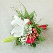 Resting on an elegantly textured pale fabric surface, evocative of Stanmore's welcoming home interiors, this compact floral arrangement is as sophisticated as it is heartfelt. A stately white lily, its large petals gracefully splayed and gently dusted with rust freckles and vivid anthers, serves as the arrangement's radiant focal point. Alongside it unfurls a velvety red rose, its rich, deep tones harmonising with the sparkling red berries nestled close by-each berry a bright echo of local holiday festivities. Interspersed, fine clouds of baby's breath and a slender green lily bud create a sense of lightness and potential, while an array of feathery green ferns and broader foliage provide a lush, textural embrace. The bouquet's stems are deftly bound with a glossy red satin ribbon, neatly echoing the deeper hues above. Crafted as both a timeless and contemporary accent, this floral creation offers the perfect accompaniment to weddings, parties, or intimate gatherings throughout Stanmore, carrying with it the freshness and care of local florists devoted to capturing joy in every bloom.